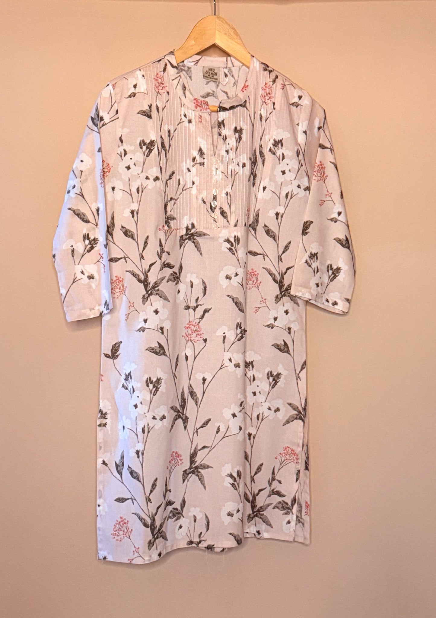Floral-patterned dress on a hanger against a beige background