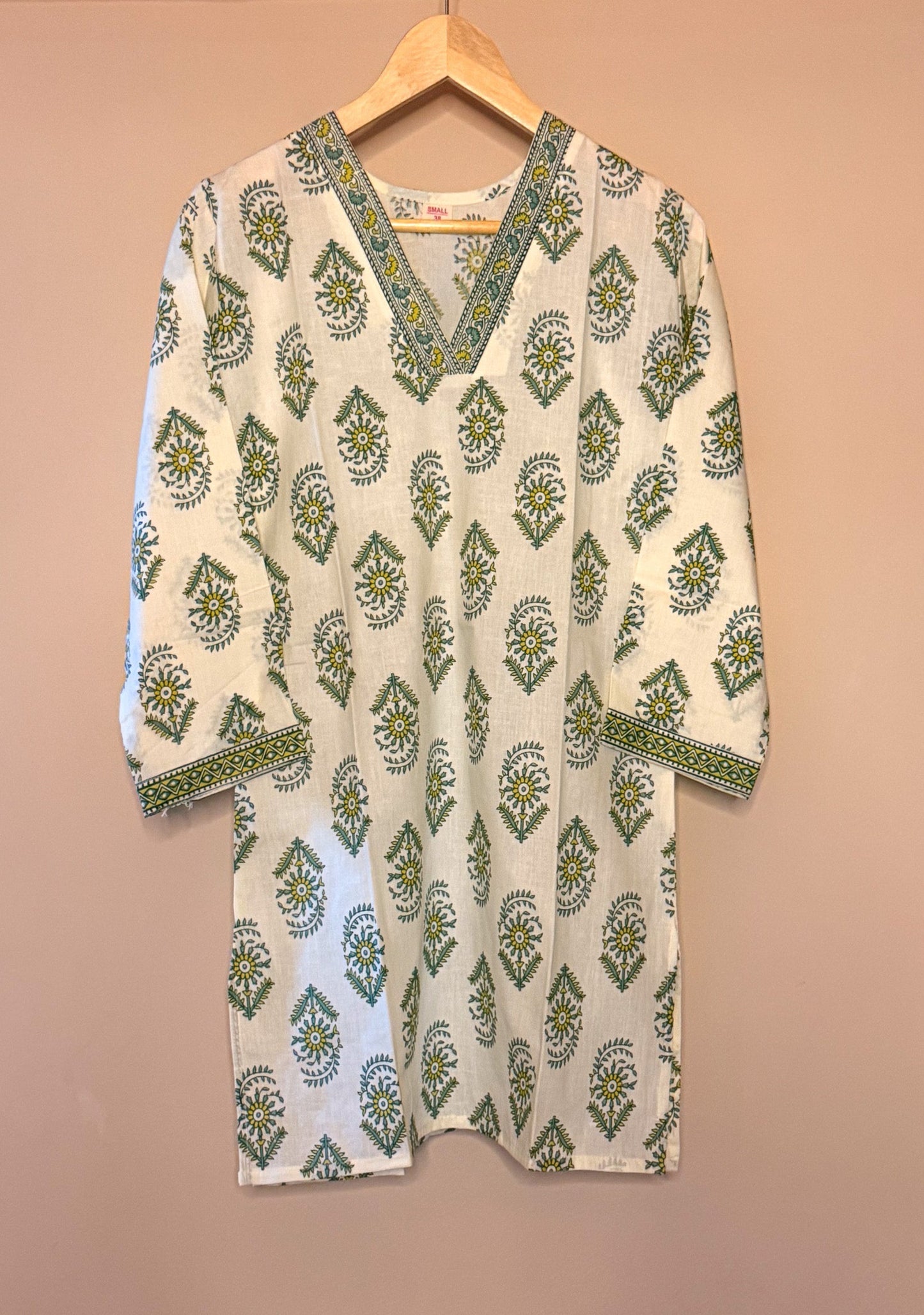 White kurta with green patterns on a beige background