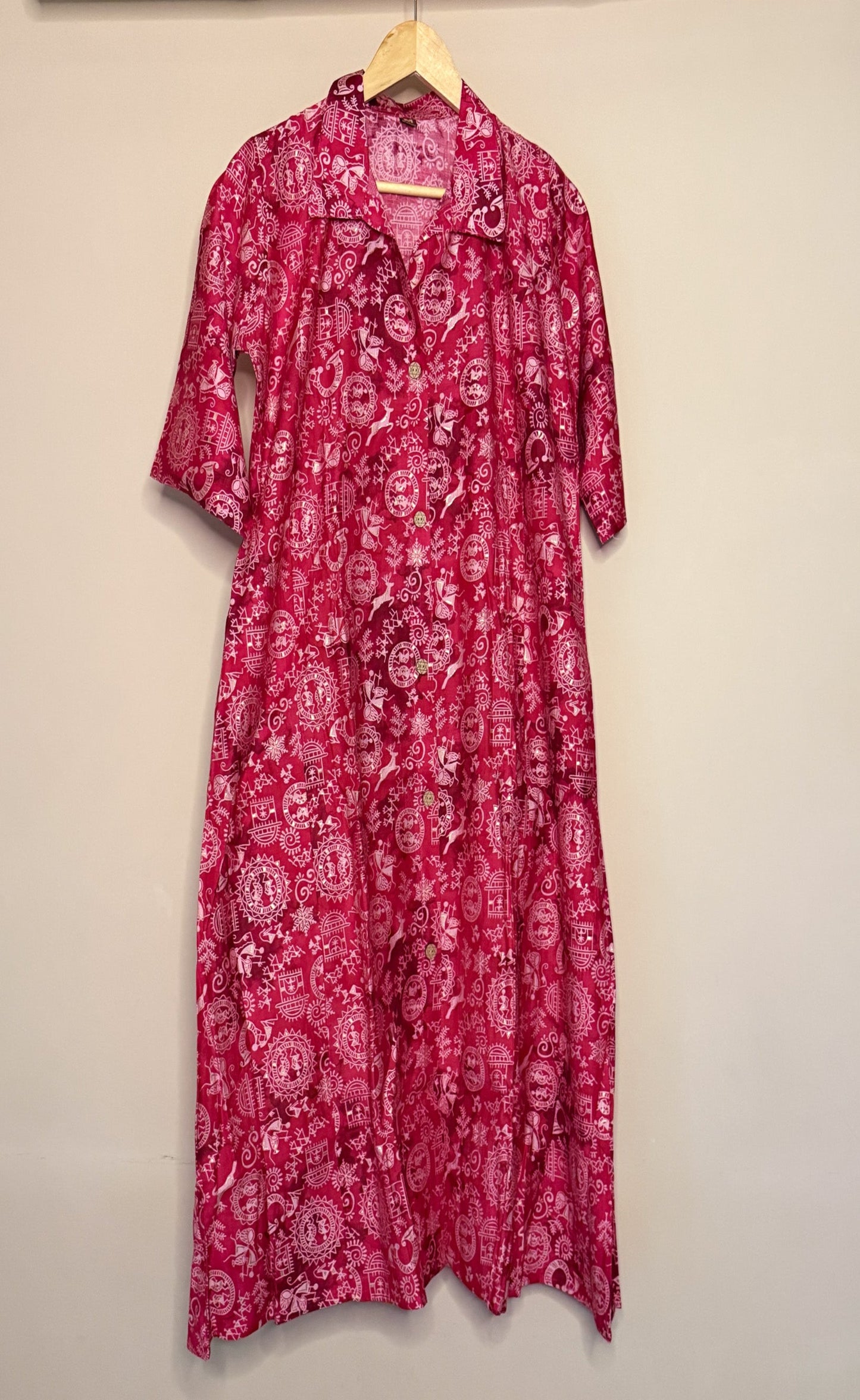 Pink Varli patterned coordset on a hanger against a beige wall