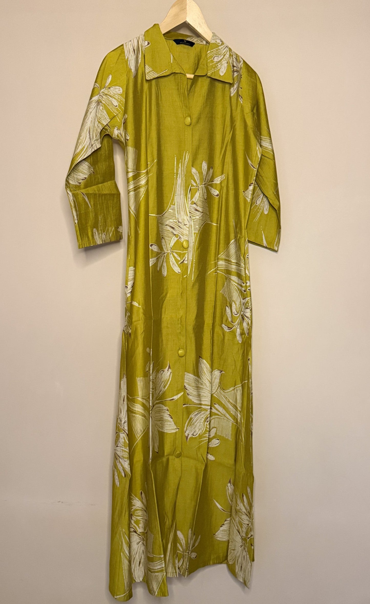 Mustard floral dress on a hanger against a beige wall