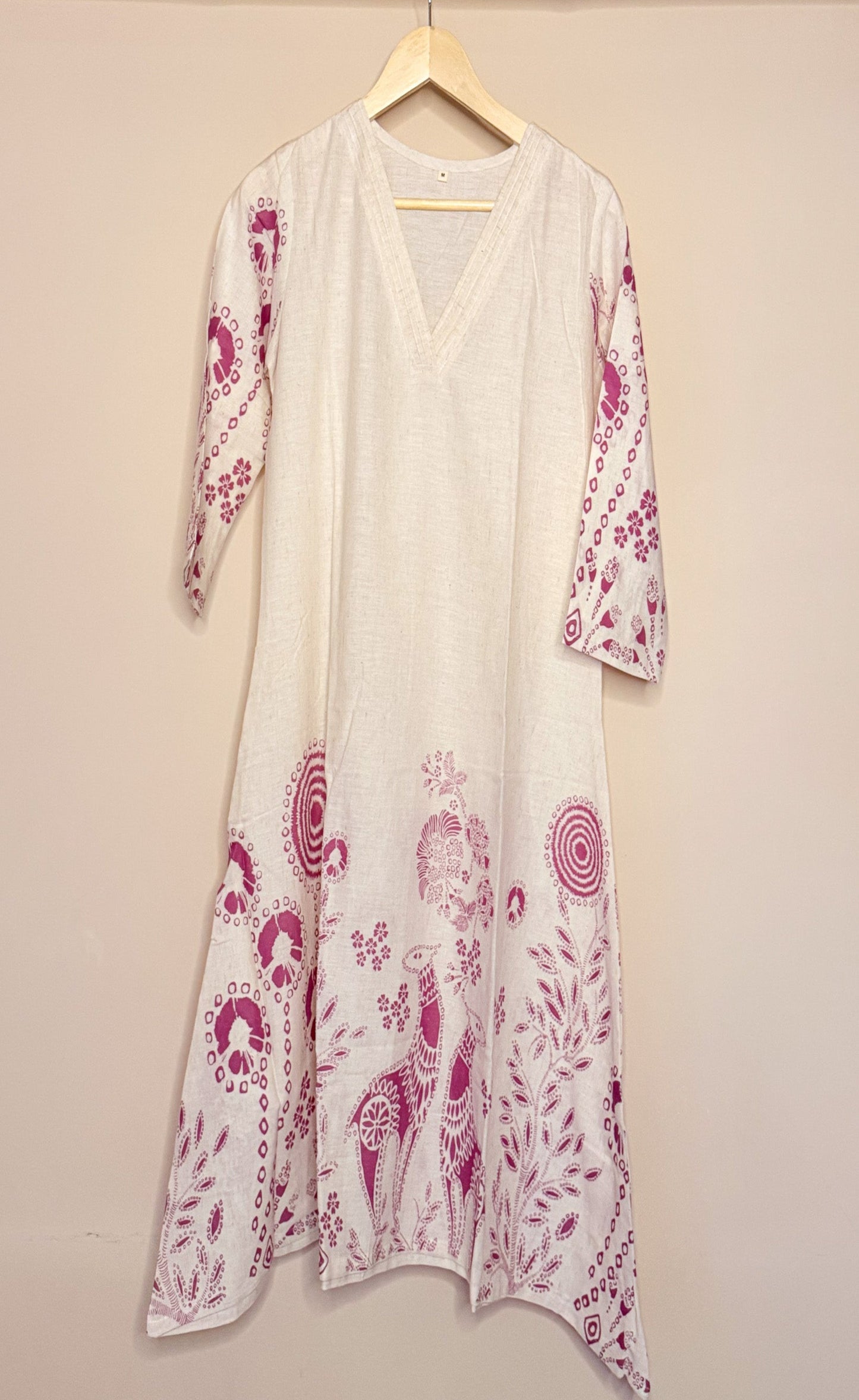 White khadi coordset with pink floral patterns on a hanger against a beige background
