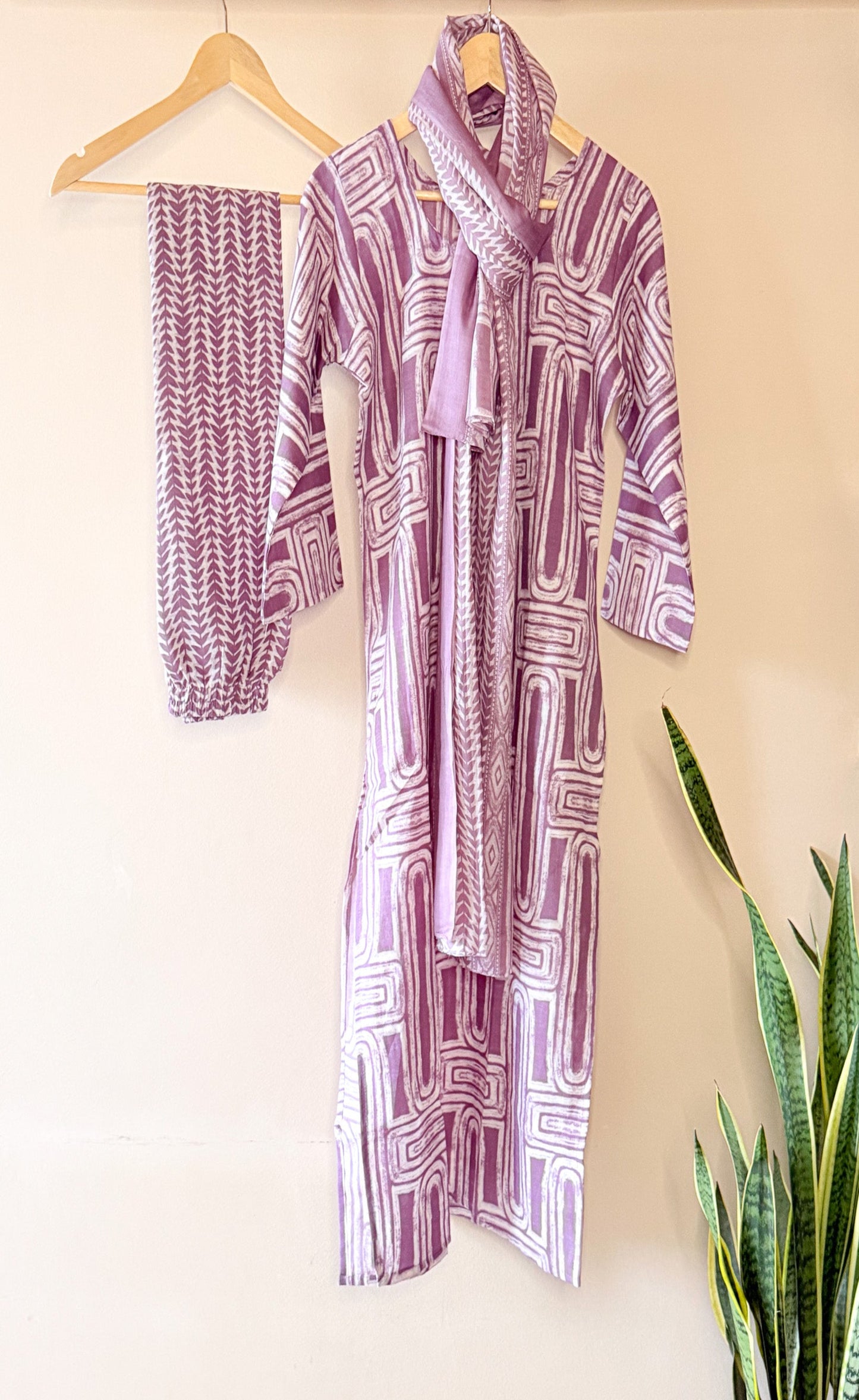 Purple patterned kurta set on a beige wall.