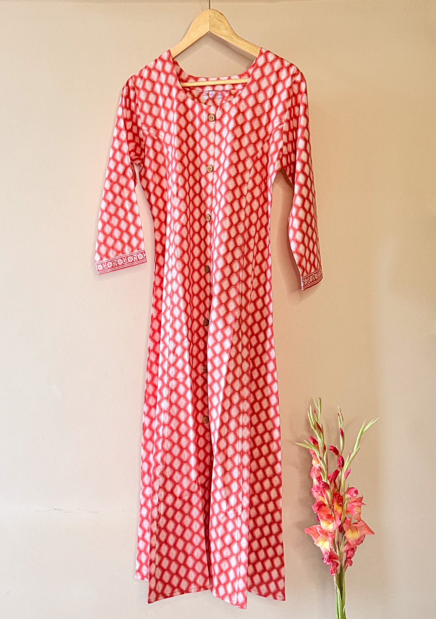 Orange patterned dress on a hanger with a blurred background