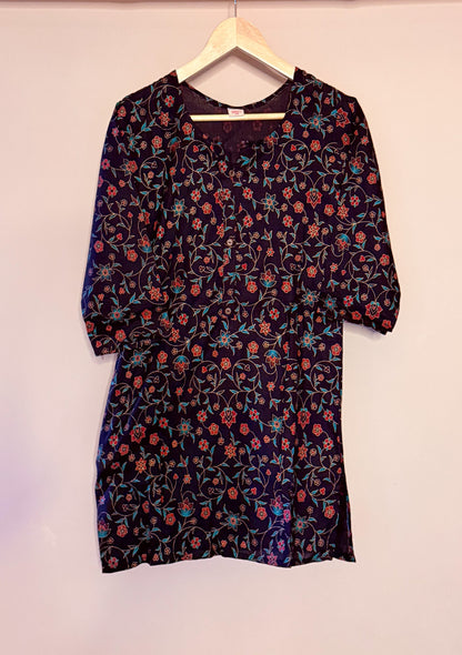 Floral-patterned black dress on a hanger against a plain background