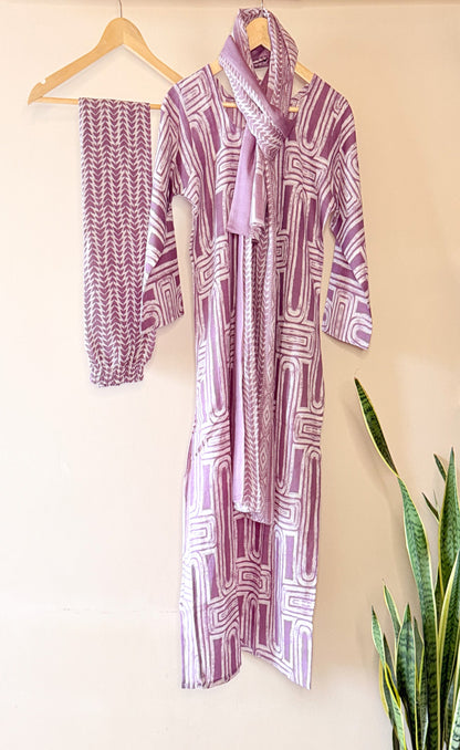 Purple patterned kurta set on a beige wall.