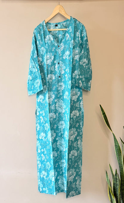 Turquoise floral dress on a hanger against a beige wall.