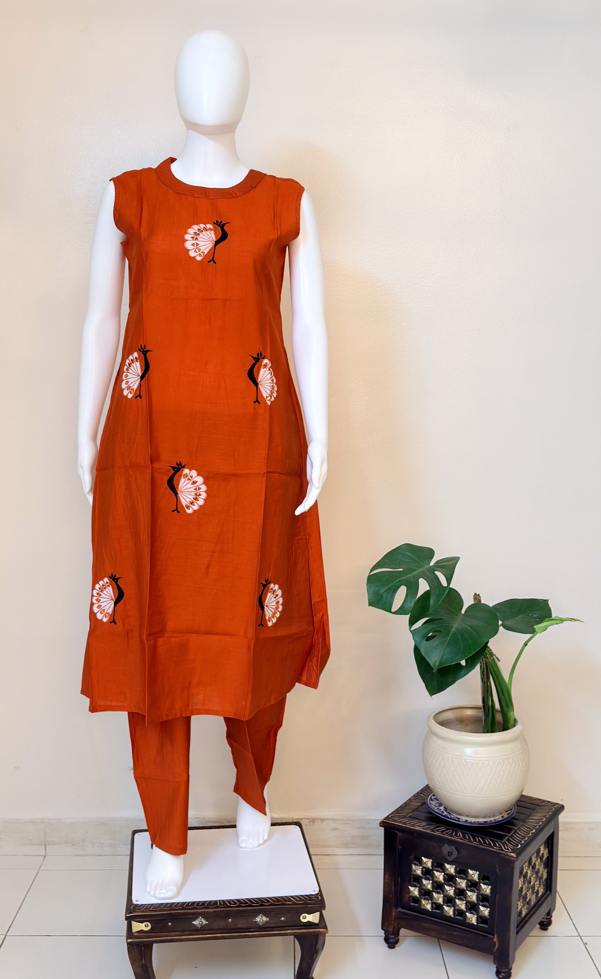 Orange coordset with morni patterns on a mannequin against a white wall.