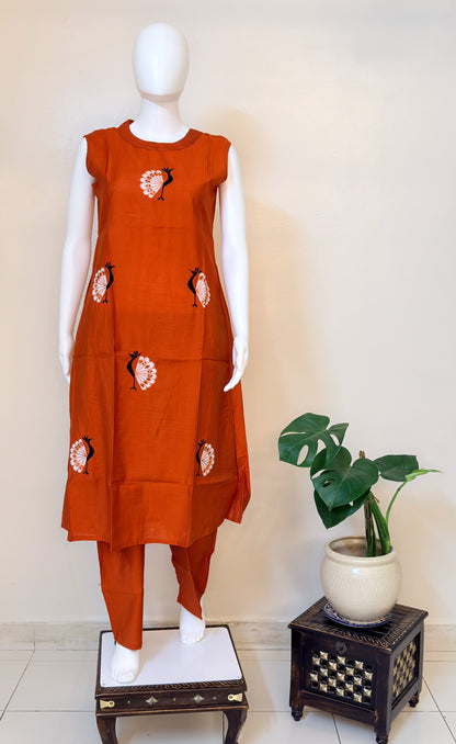 Orange coordset with morni patterns on a mannequin against a white wall.