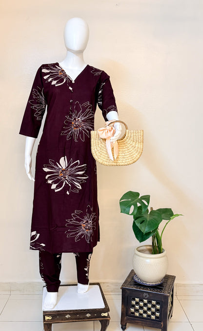 Mannequin wearing a dark coffee colour coordset with floral patterns, holding a straw bag, against a light background.