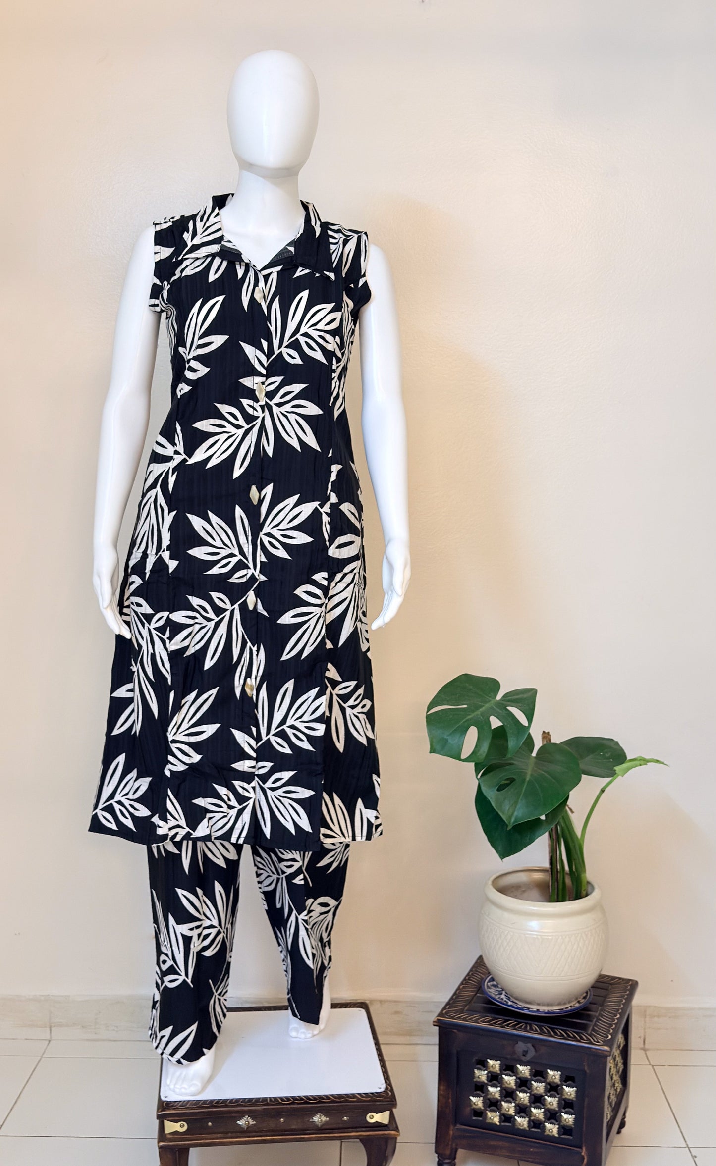 Mannequin wearing a black coordset with white leaf pattern.